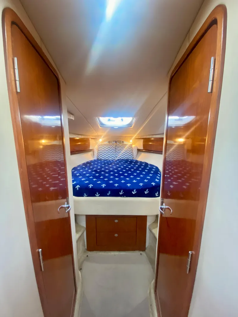 Slide: The Image of 2005 Sea Ray 420 Sundancer cabin with double bed and wooden doors. - 49