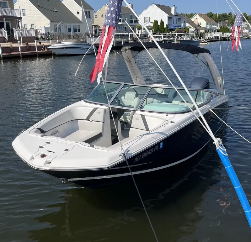 Slide: The Image of 2017 Regal 23 OBX boat docked in a residential marina with American flags. - 2