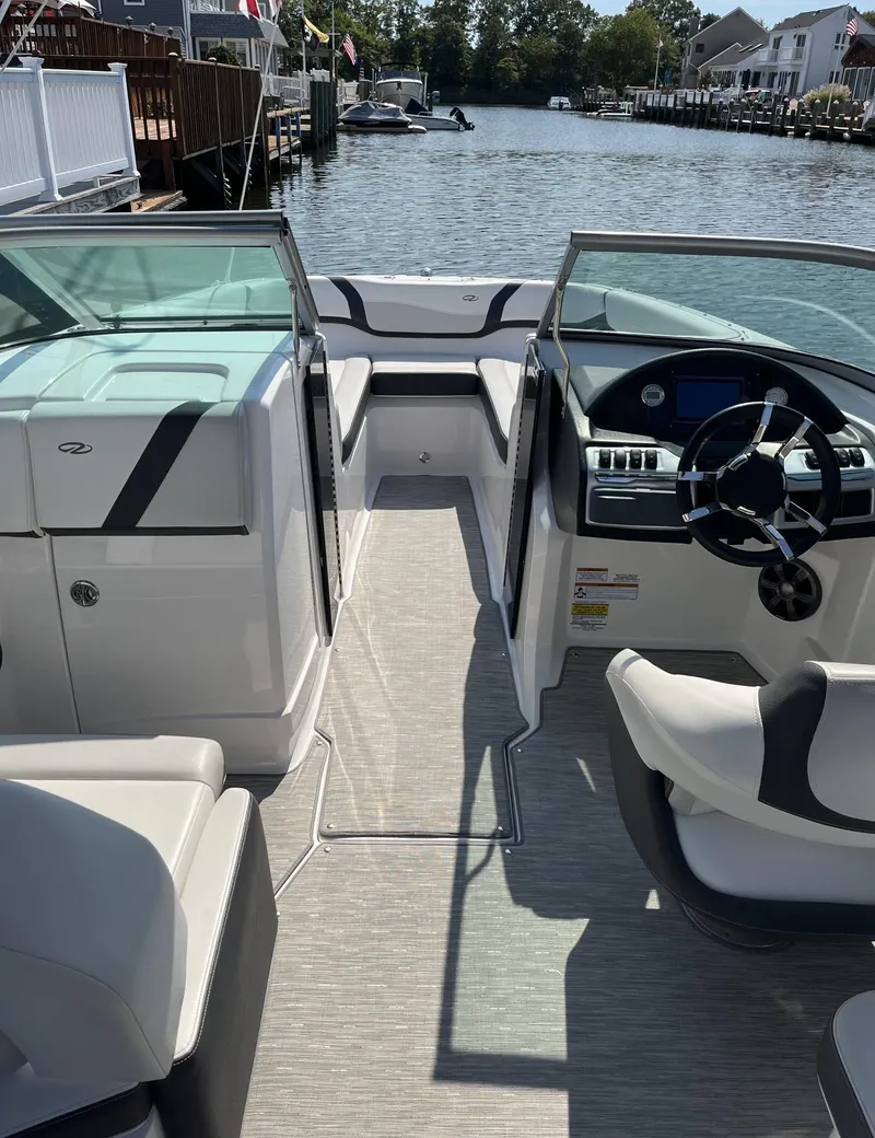 Slide: The Image of 2017 Regal 23 OBX boat interior with steering wheel, seating, and open deck on a sunny day. - 4
