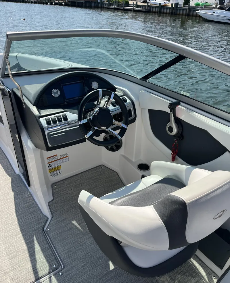 Slide: The Image of 2017 Regal 23 OBX boat cockpit with steering wheel and dashboard by the water. - 6