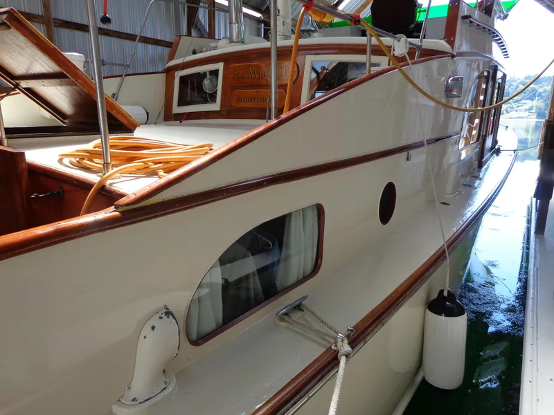 Slide: The Image of 1946 Monk Flybridge Sedan boat docked in a marina, showcasing classic wooden design. - 12