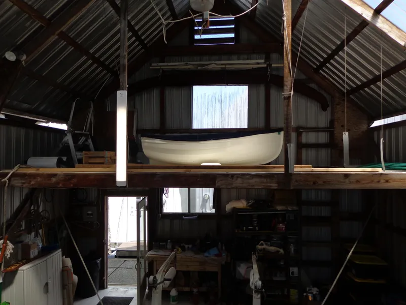 Slide: The Image of 1946 Monk Flybridge Sedan boat stored in a rustic, metal-roofed barn. - 26