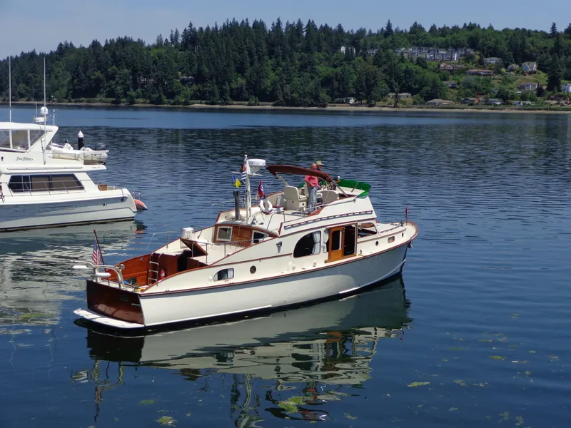 Slide: The Image of 1946 Monk Flybridge Sedan boat on calm water, surrounded by scenic greenery. - 3