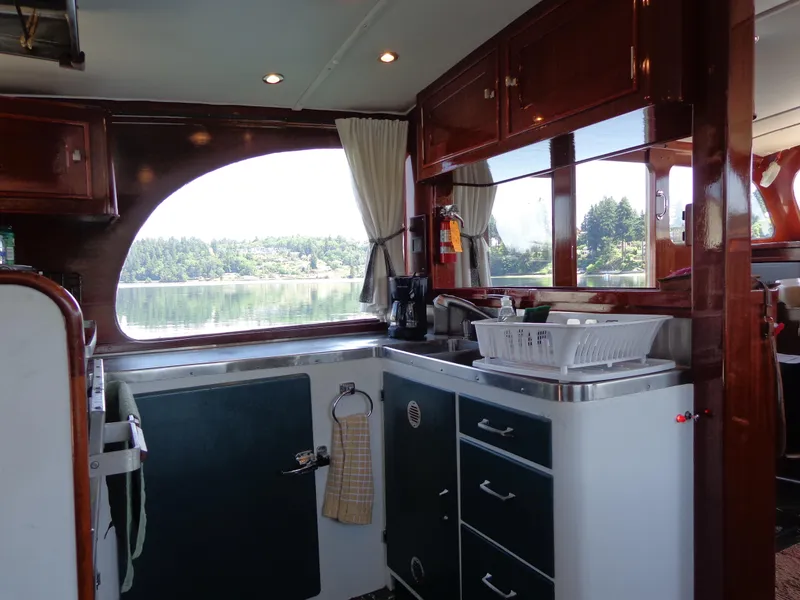 Slide: The Image of 1946 Monk Flybridge Sedan kitchen with wooden cabinets and scenic window view. - 33
