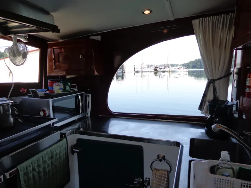 Slide: The Image of Interior of 1946 Monk Flybridge Sedan boat with kitchen view and marina backdrop. - 37