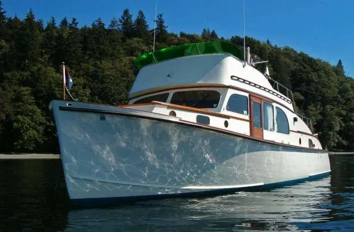 Slide: The Image of 1946 Monk Flybridge Sedan boat on calm water with forested background. - 4