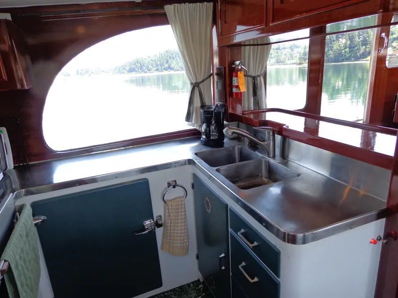 Slide: The Image of 1946 Monk Flybridge Sedan kitchen with stainless steel sink and scenic window view. - 48