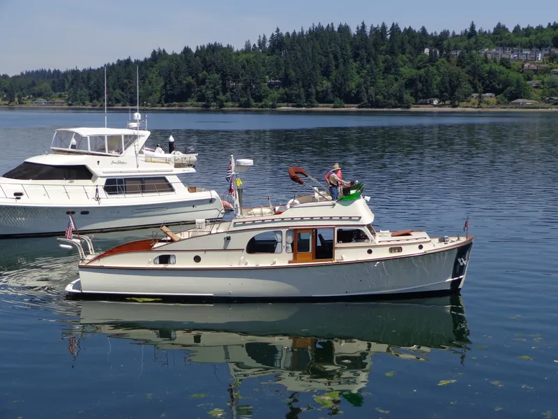 Slide: The Image of 1946 Monk Flybridge Sedan boat on calm water with forested shoreline background. - 8