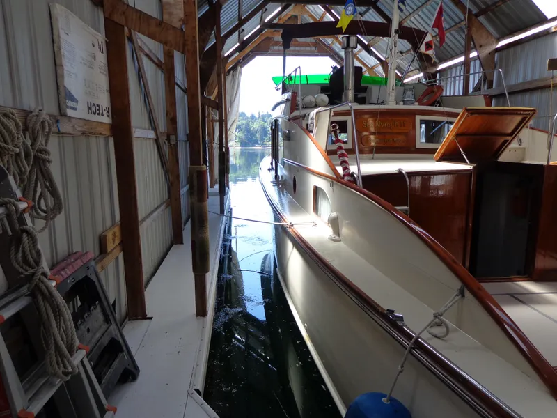 Slide: The Image of 1946 Monk Flybridge Sedan docked in a covered boathouse. - 9