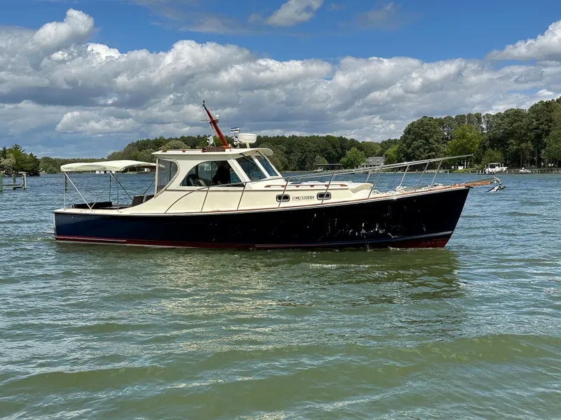 Slide: The Image of 2001 Mast & Mallet 38 Picnic Boat on calm water under a partly cloudy sky. - 2