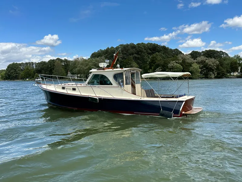 Slide: The Image of 2001 Mast & Mallet 38 Picnic Boat on a serene lake with lush green trees. - 22