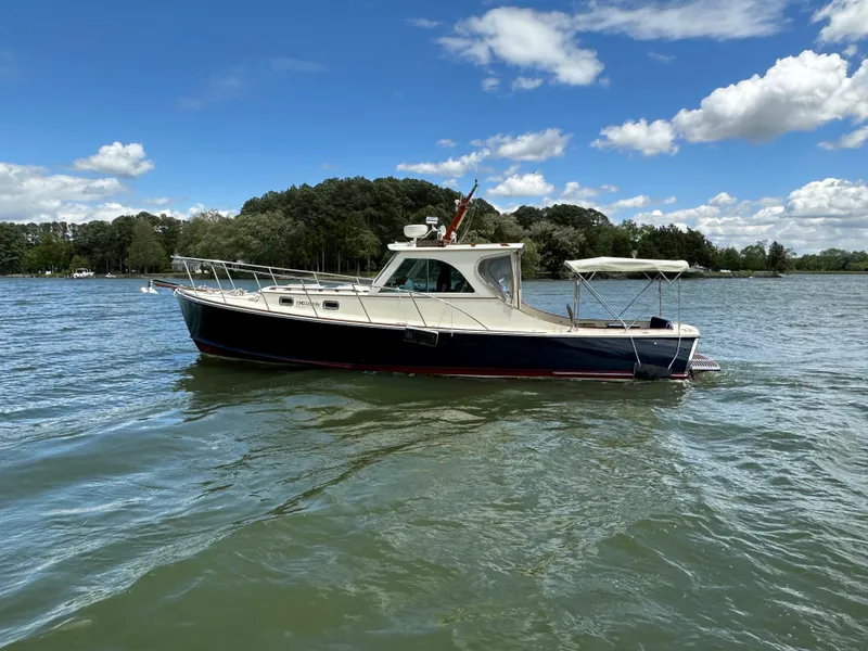 Slide: The Image of 2001 Mast & Mallet 38 Picnic Boat on a serene lake under a blue sky. - 25