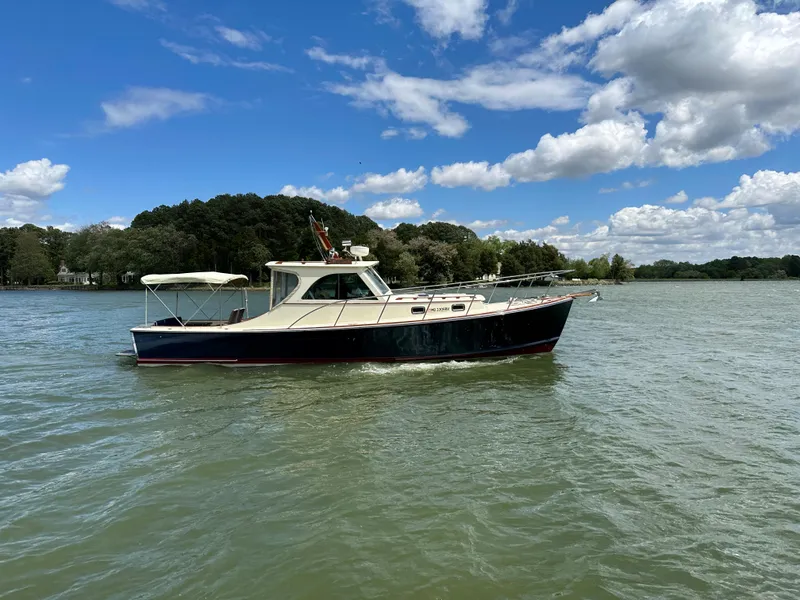 Slide: The Image of 2001 Mast & Mallet 38 Picnic Boat cruising on a serene lake under a blue sky. - 5