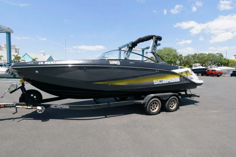 Slide: The Image of 2017 Scarab 255 HO Impulse boat on a trailer in a parking lot. - 3