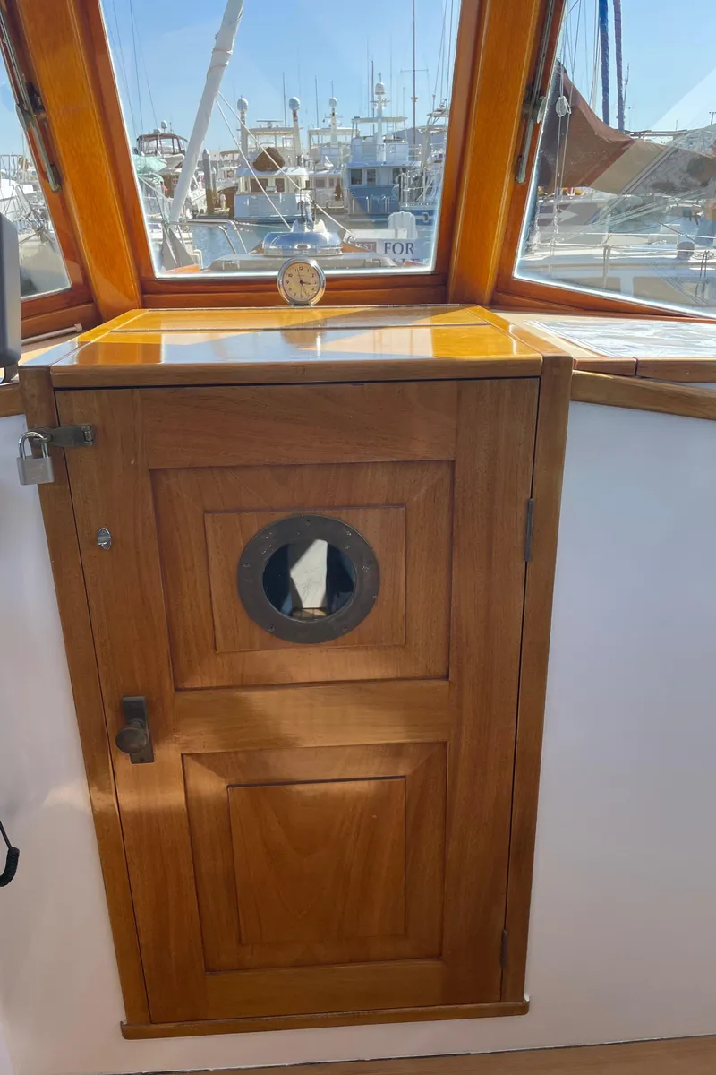 Slide: The Image of Wooden cabin door on a 1996 Downeast 36 Lobster Boat, with a porthole and marina view. - 23