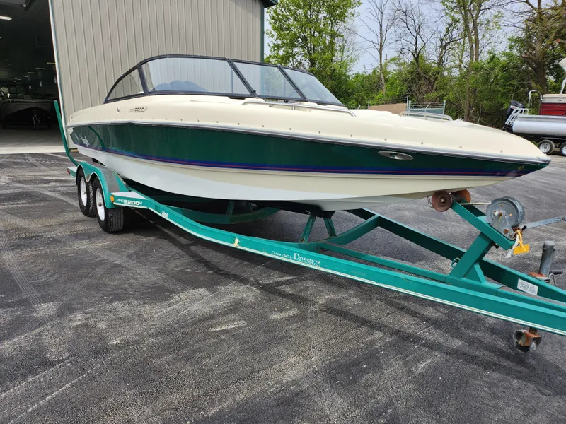 Slide: The Image of 1998 Tigé PRE 2200I boat on a teal trailer outside a storage facility. - 2
