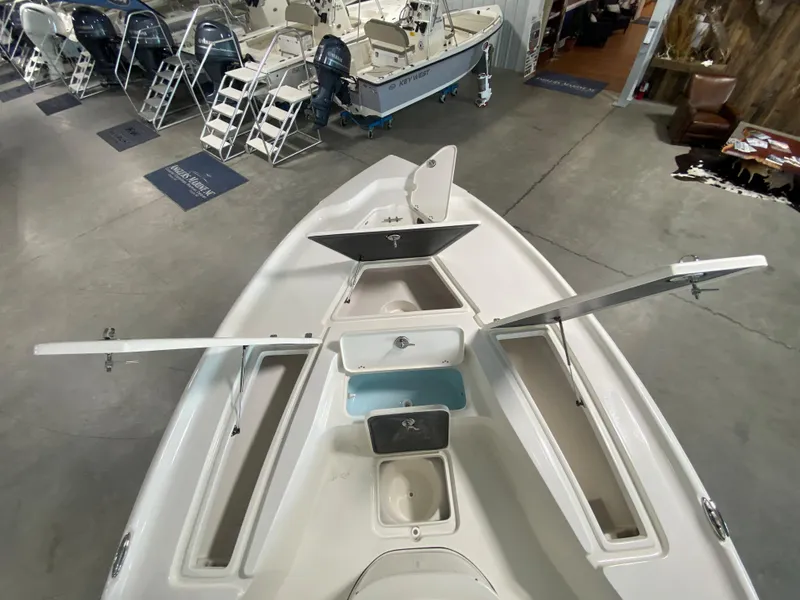 Slide: The Image of 2024 Key West 250 Bay Reef boat with open storage compartments in a showroom. - 14