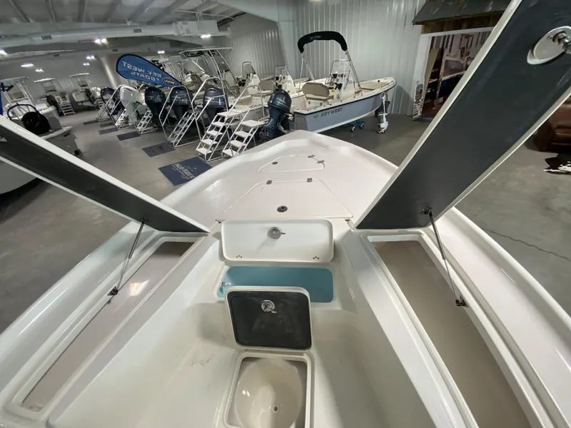 Slide: The Image of 2024 Key West 250 Bay Reef boat interior, open storage compartments, showroom display. - 13