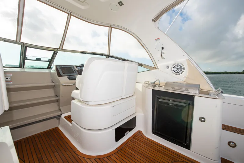 Slide: The Image of 2009 Sea Ray 350 Sundancer cockpit with helm, seating, and mini-fridge. - 18
