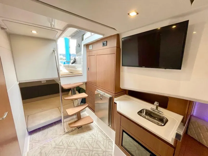 Slide: The Image of Interior of 2025 Schaefer 375 yacht with kitchenette, TV, and wooden stairs. - 36