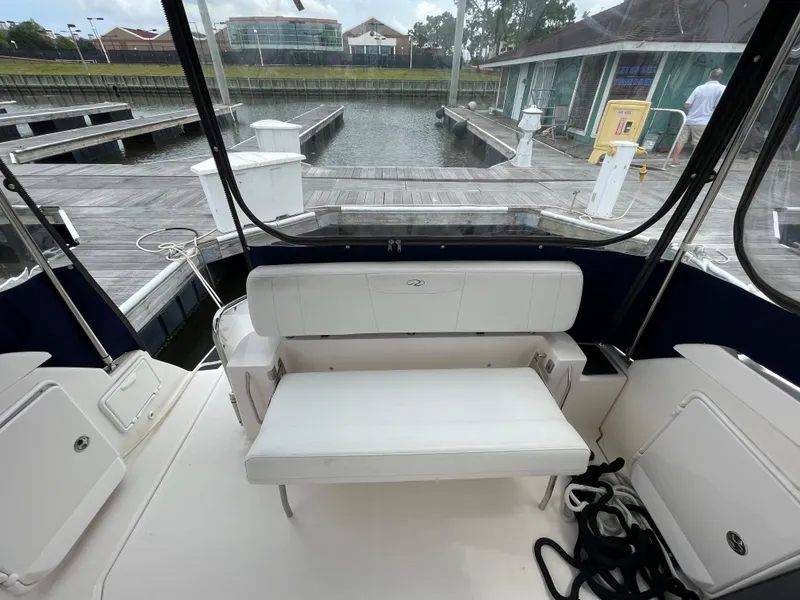 Slide: The Image of 2006 Regal 3060 Window Express boat interior with white seating at a marina. - 12