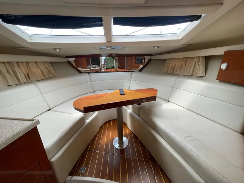 Slide: The Image of Interior of 2006 Regal 3060 Window Express boat with white seating and wooden table. - 19
