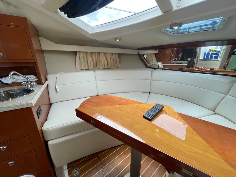 Slide: The Image of Interior of 2006 Regal 3060 Window Express yacht with white leather seating and wooden table. - 20