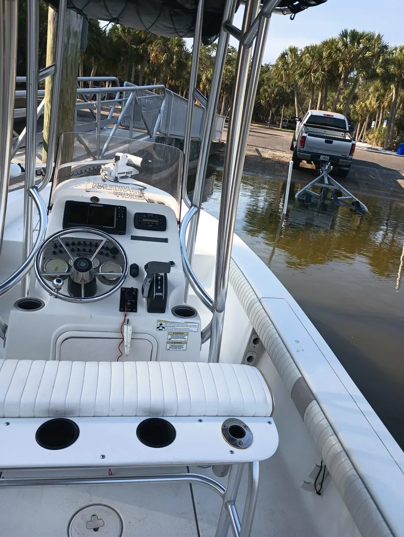 Slide: The Image of 2014 Carolina Skiff Sea Skiff 21 boat at a dock with a truck in the background. - 9