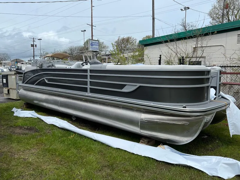 Slide: The Image of 2023 Lowe 250 pontoon boat on display at a dealership. - 2