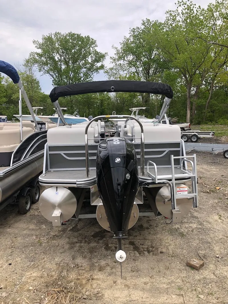 Slide: The Image of 2023 Lowe 250 pontoon boat with outboard motor, parked on land. - 4