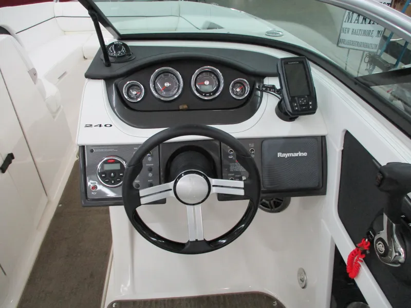 Slide: The Image of 2015 Sea Ray 240 Sundeck dashboard with steering wheel and navigation instruments. - 16