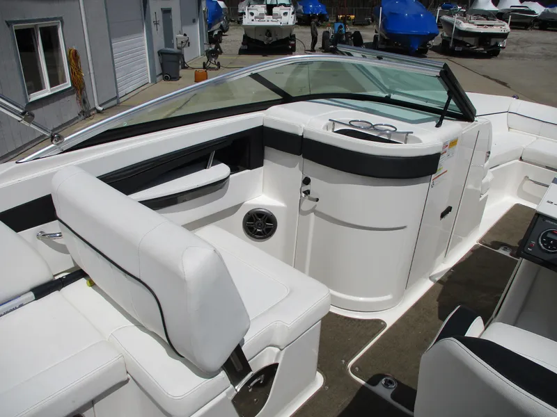 Slide: The Image of 2015 Sea Ray 240 Sundeck interior with white seating and dashboard, docked at marina. - 9