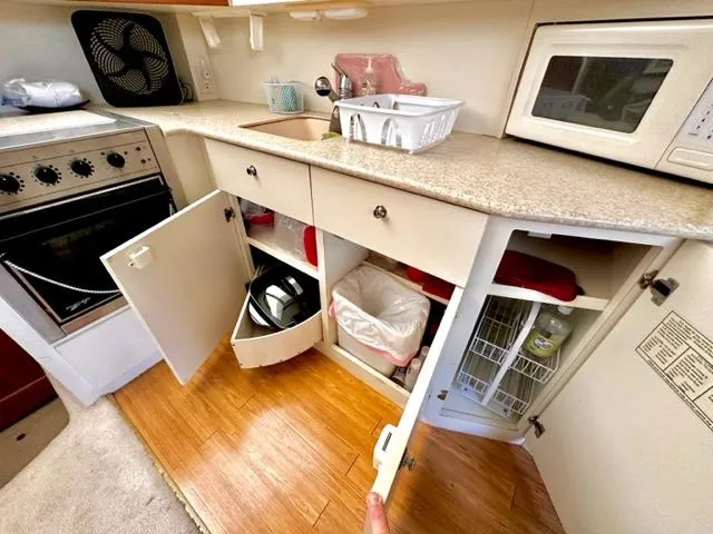 Slide: The Image of 2000 Silverton 392 Motor Yacht kitchen with open cabinets, stove, and microwave. - 10