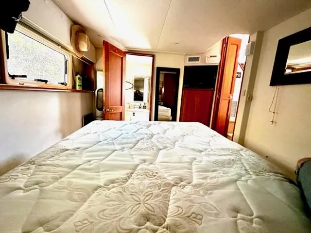 Slide: The Image of 2000 Silverton 392 Motor Yacht bedroom with bed, window, and wooden cabinets. - 13