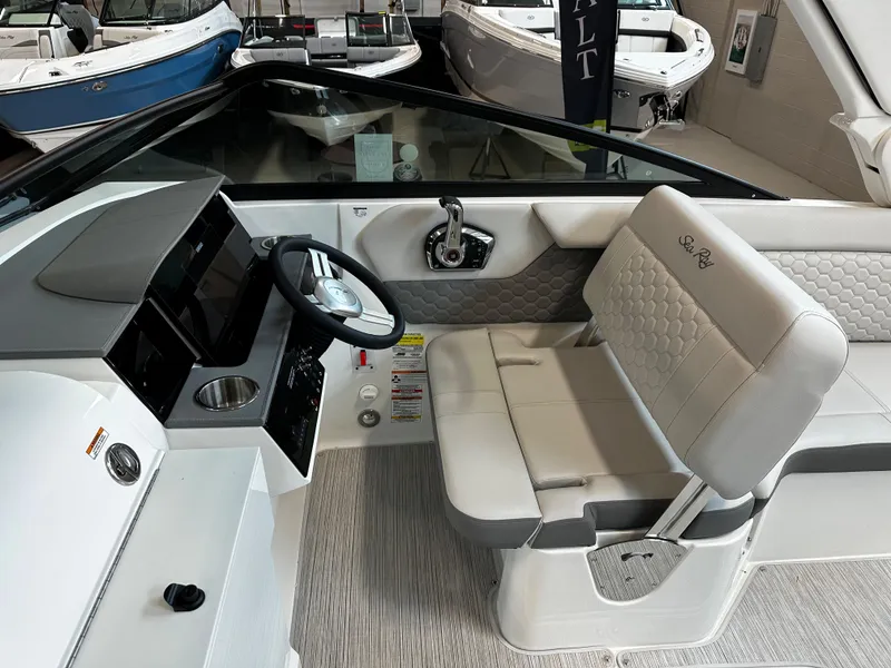 Slide: The Image of 2023 Sea Ray SDX 250 boat interior with helm, steering wheel, and cushioned seating. - 14