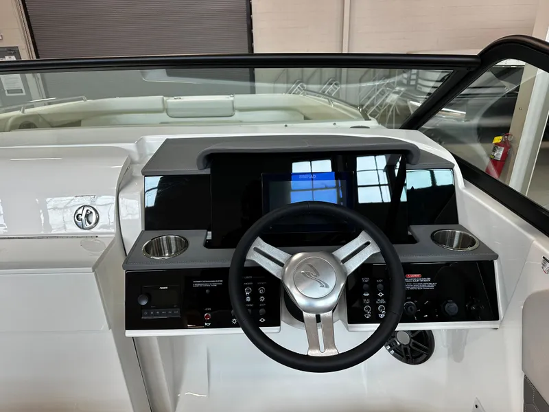 Slide: The Image of 2023 Sea Ray SDX 250 helm with steering wheel, digital display, and cup holders. - 16