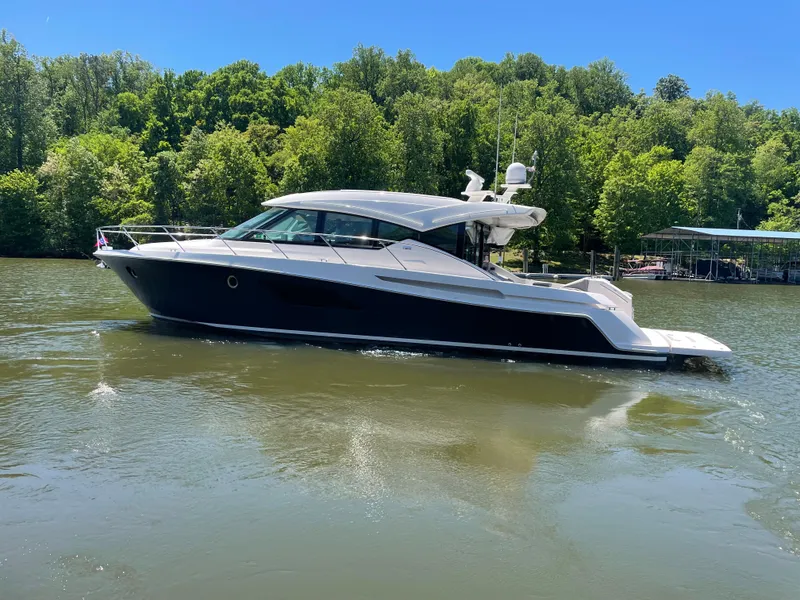 Slide: The Image of 2019 Tiara Yachts C53 cruising on a serene lake with lush green trees. - 1