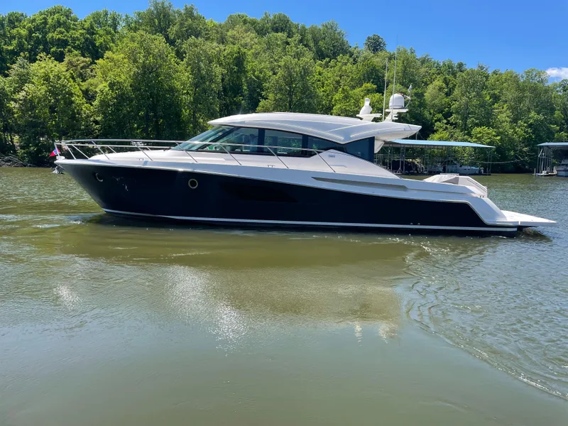 Slide: The Image of 2019 Tiara Yachts C53 cruising on a serene lake with lush green trees. - 3
