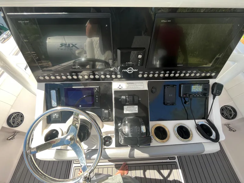 Slide: The Image of 2018 Fountain 34 CC boat dashboard with steering wheel, controls, and navigation screens. - 12