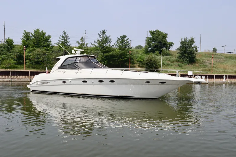 Slide: The Image of 2001 Sea Ray 460 Sundancer yacht docked on calm water, surrounded by greenery. - 48