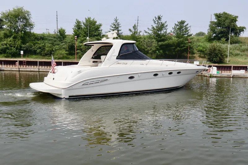 Slide: The Image of 2001 Sea Ray 460 Sundancer yacht cruising on a calm river near a green shoreline. - 49