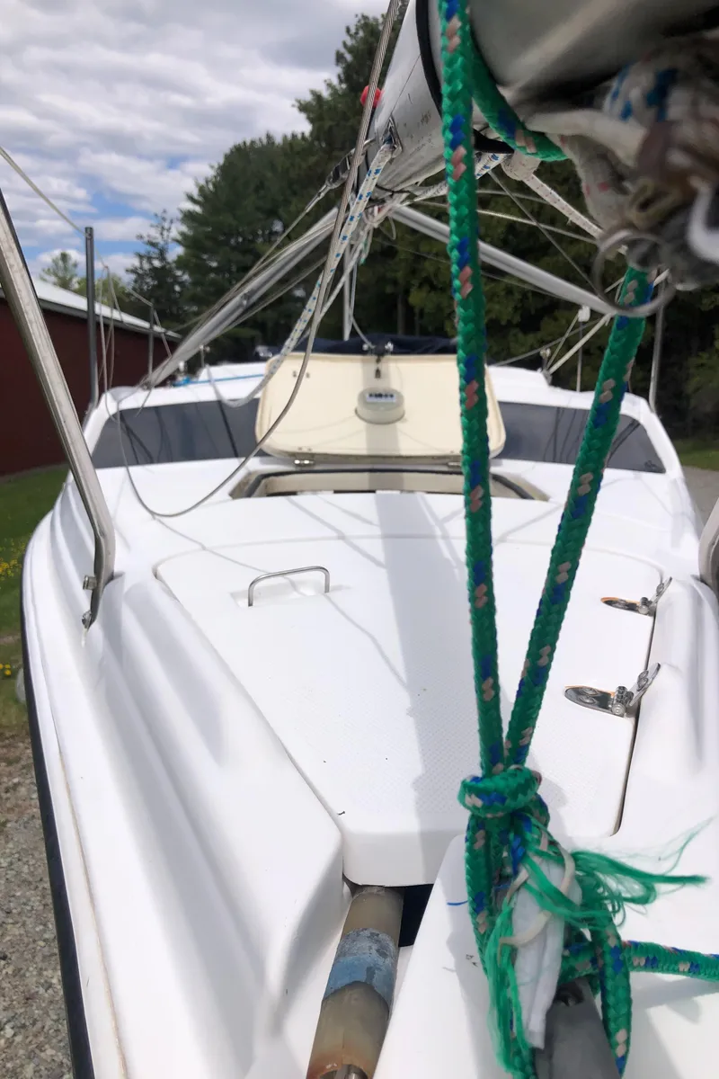 Slide: The Image of 1998 Hunter 240 sailboat with green ropes, docked outdoors under cloudy sky. - 10