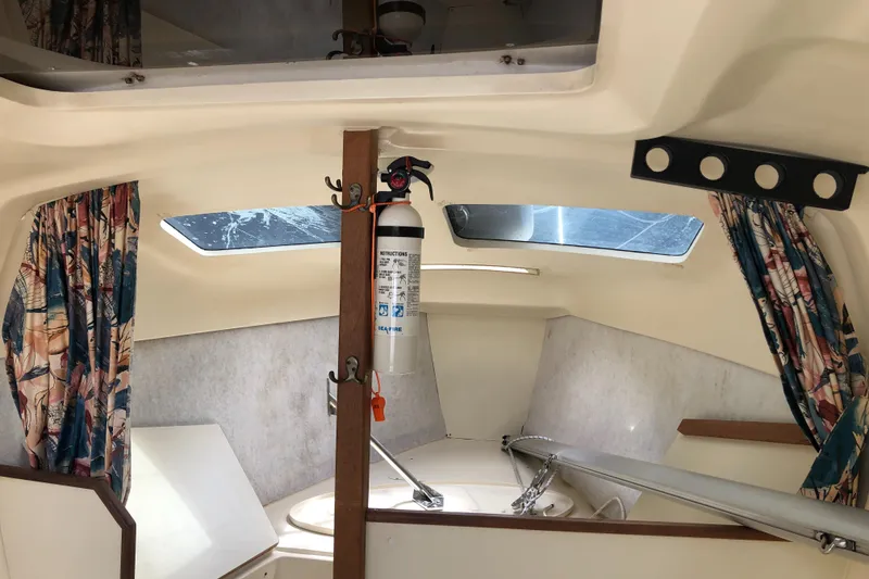 Slide: The Image of Interior of a 1998 Hunter 240 sailboat with colorful curtains and a fire extinguisher. - 17
