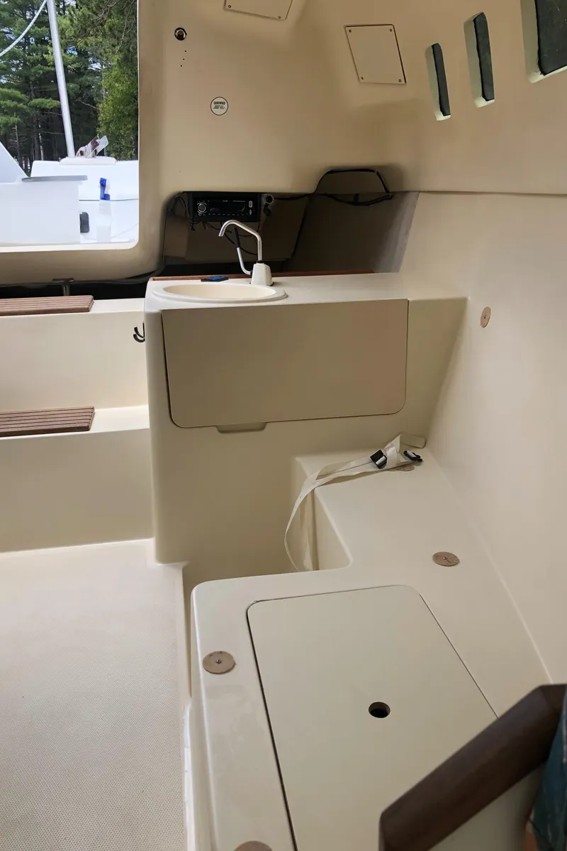 Slide: The Image of Interior of a 1998 Hunter 240 sailboat, featuring a compact kitchenette and seating area. - 24