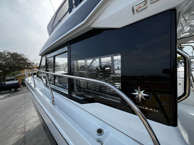 Slide: The Image of 2024 Jeanneau NC Weekender 1295 Fly yacht side view with sleek design and reflective windows. - 10