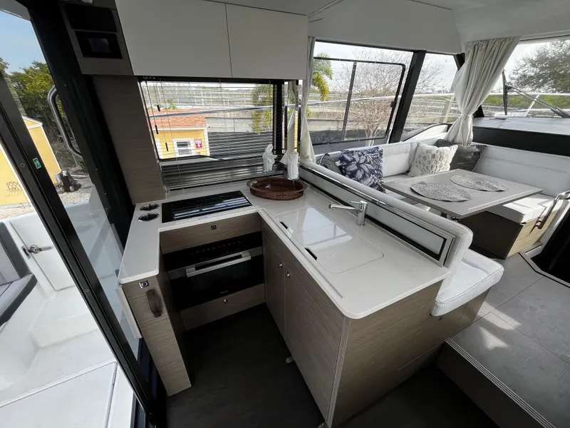Slide: The Image of Modern kitchen and seating area inside the 2024 Jeanneau NC Weekender 1295 Fly. - 13