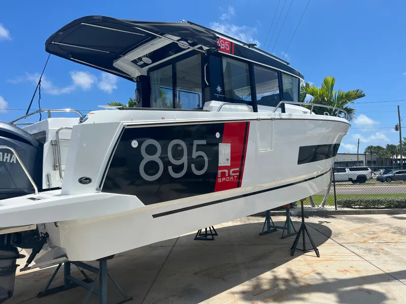 Slide: The Image of 2024 Jeanneau NC Sport 895 boat on stands under a clear blue sky. - 4