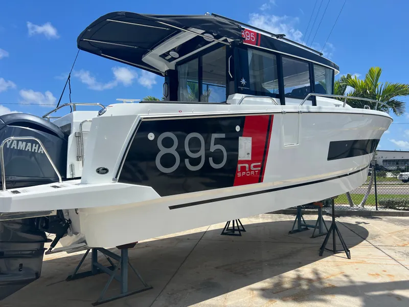 Slide: The Image of 2026 Jeanneau NC Sport 895 cruising on turquoise water near coastal homes. - 1