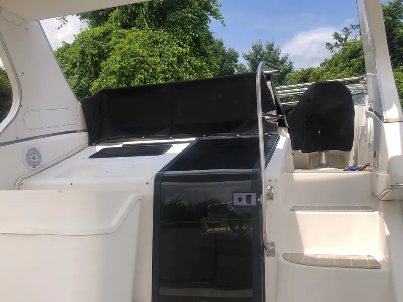 Slide: The Image of 1996 Bayliner 3587 Motoryacht with black covers, white deck, and lush green backdrop. - 11