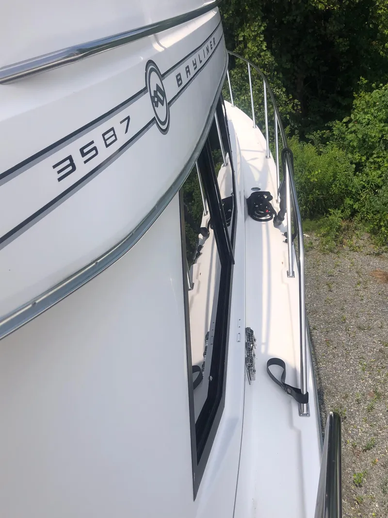 Slide: The Image of 1996 Bayliner 3587 Motoryacht side view with railing and lush greenery background. - 14